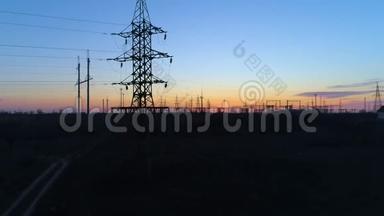 电力设施，无人驾驶飞机在黄昏时穿过高压电塔架在蓝天上移动